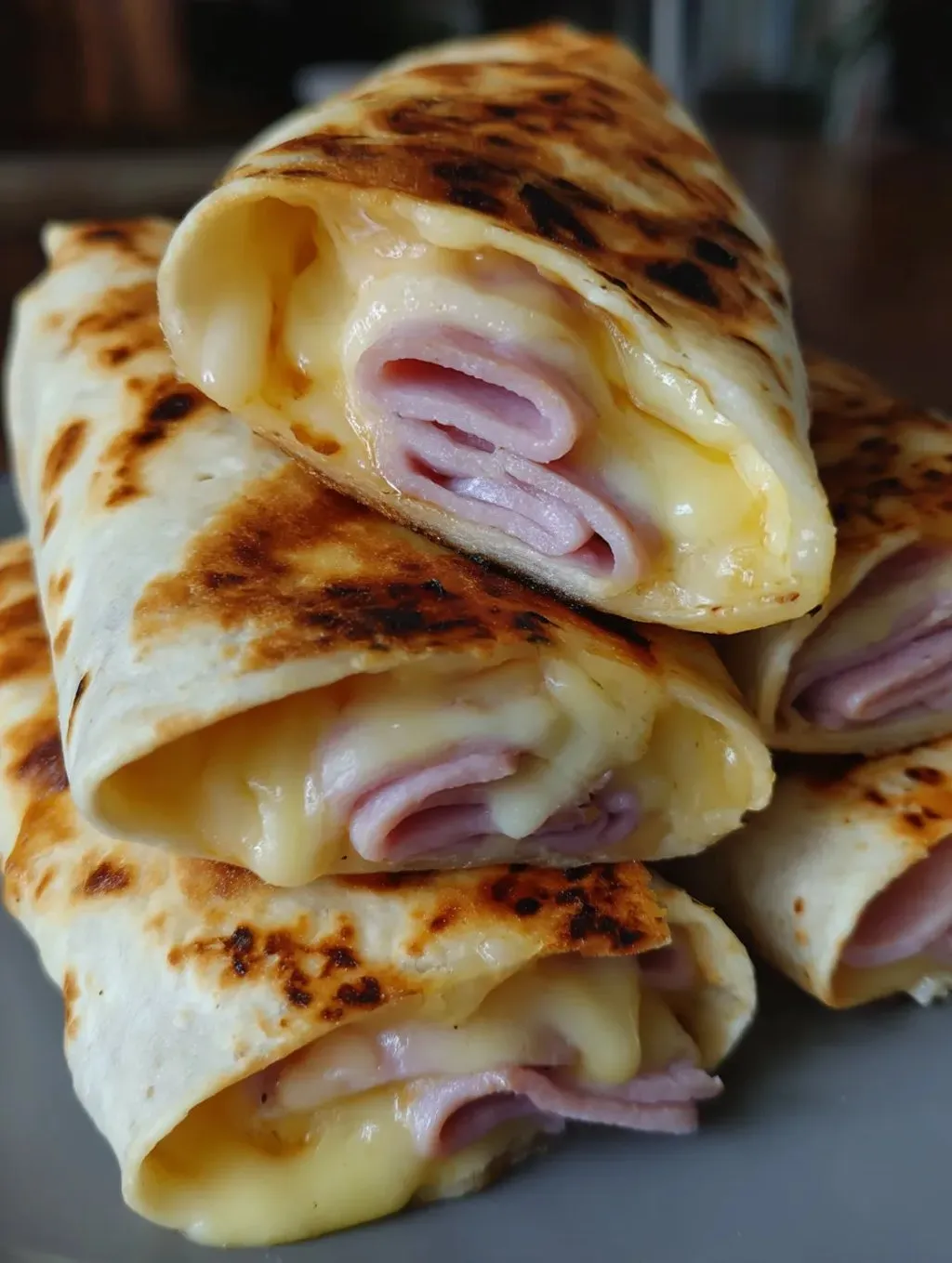 A stack of burritos with cheese and meat.