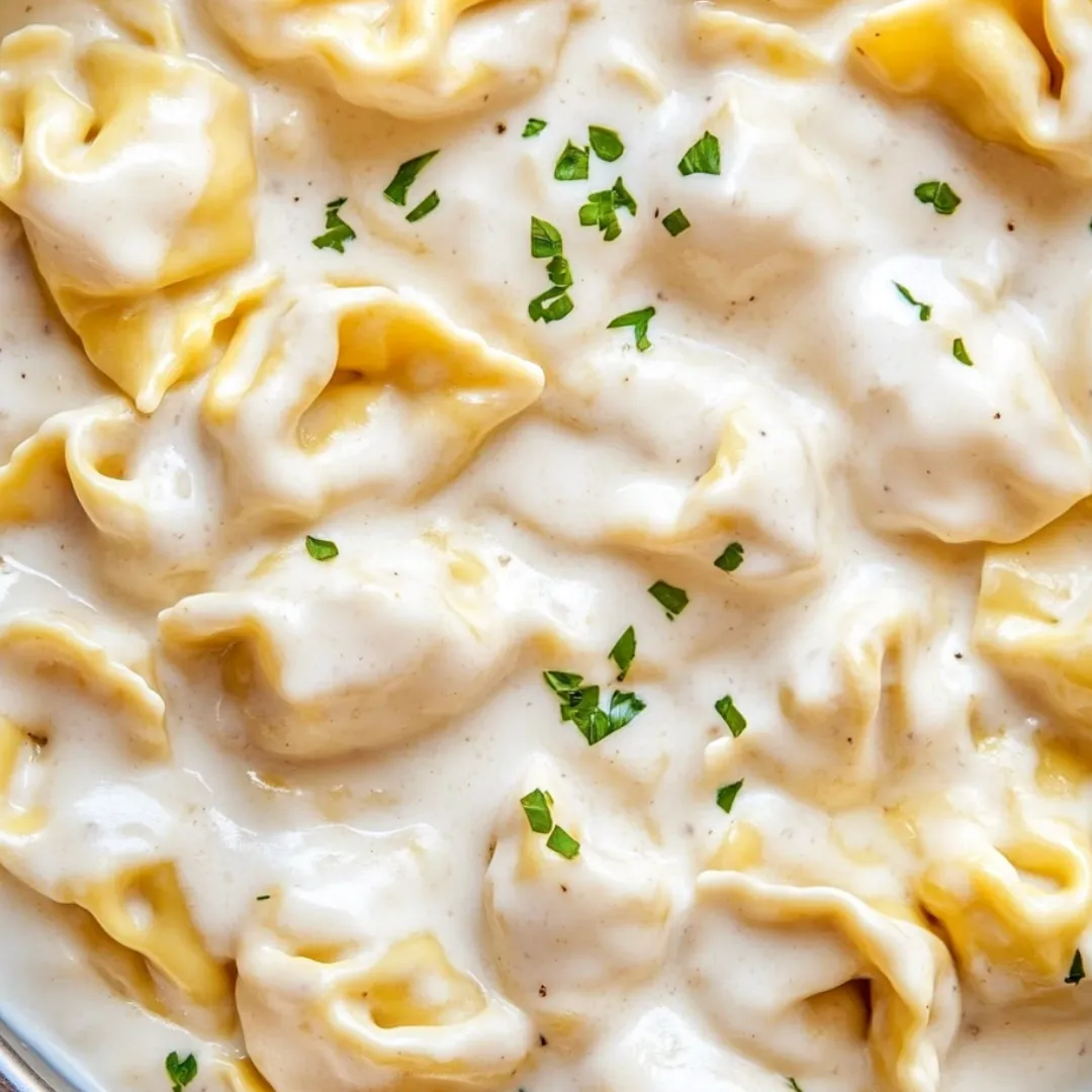 A bowl of pasta with green herbs on top.