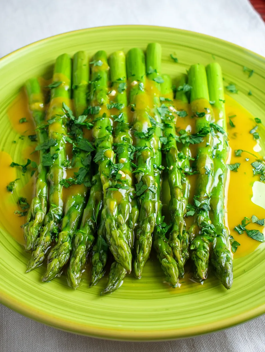 A plate of cooked asparagus with sauce.