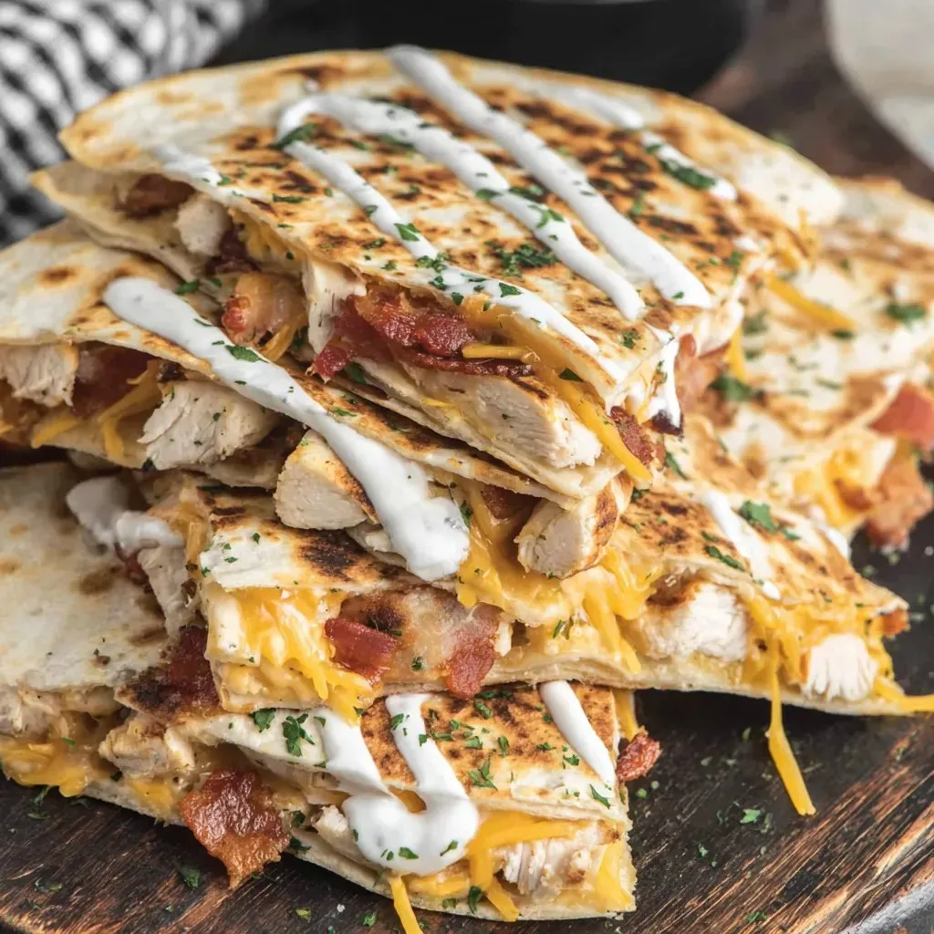 A stack of chicken sandwiches with cheese and bacon.