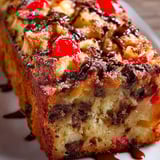 A slice of cake with chocolate and cherries.