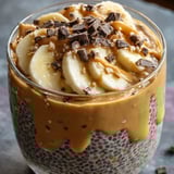 A glass of yogurt with bananas and chocolate chips.