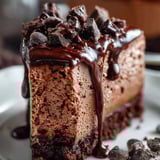 A slice of chocolate cake with chocolate drizzle.