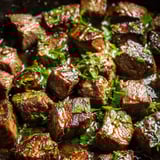 A close up of beef stew with green herbs.