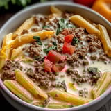 A bowl of pasta with meat and tomatoes.