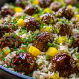 A bowl of rice with meatballs and vegetables.