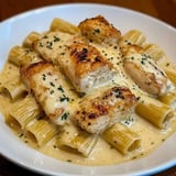 A plate of pasta with chicken on top.