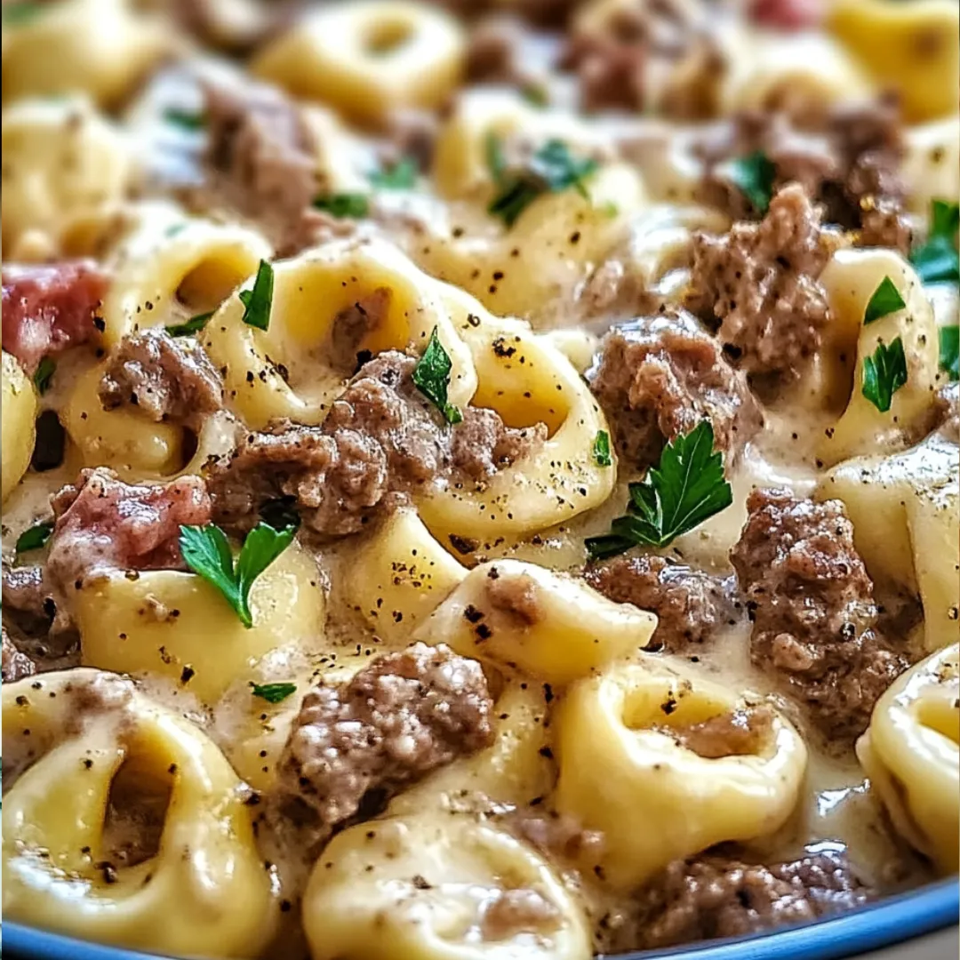 A bowl of pasta with meat and cheese on top.