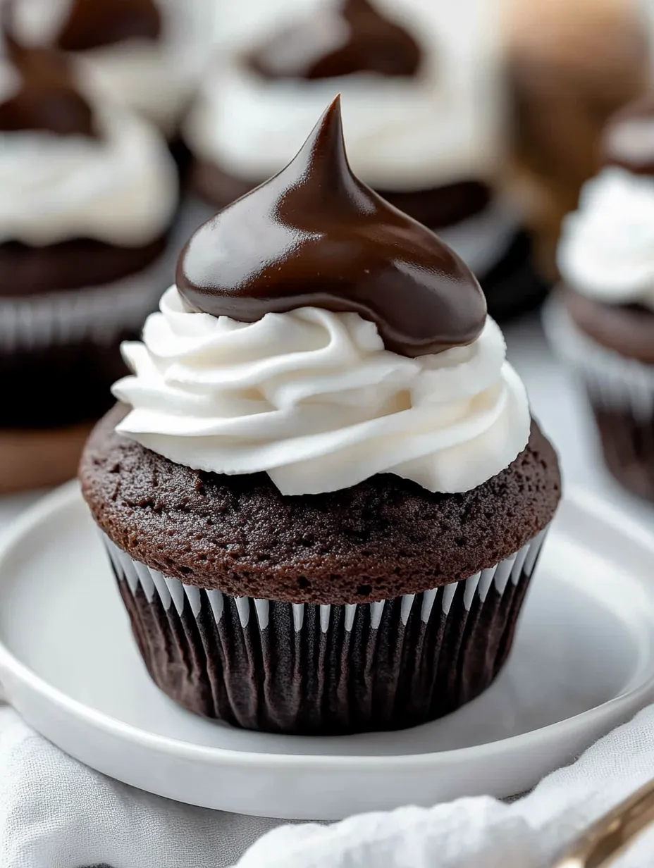 A cupcake with chocolate frosting and white whipped cream on top.