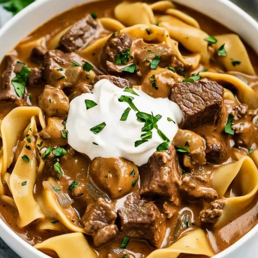 A bowl of pasta with meat and cheese on top.