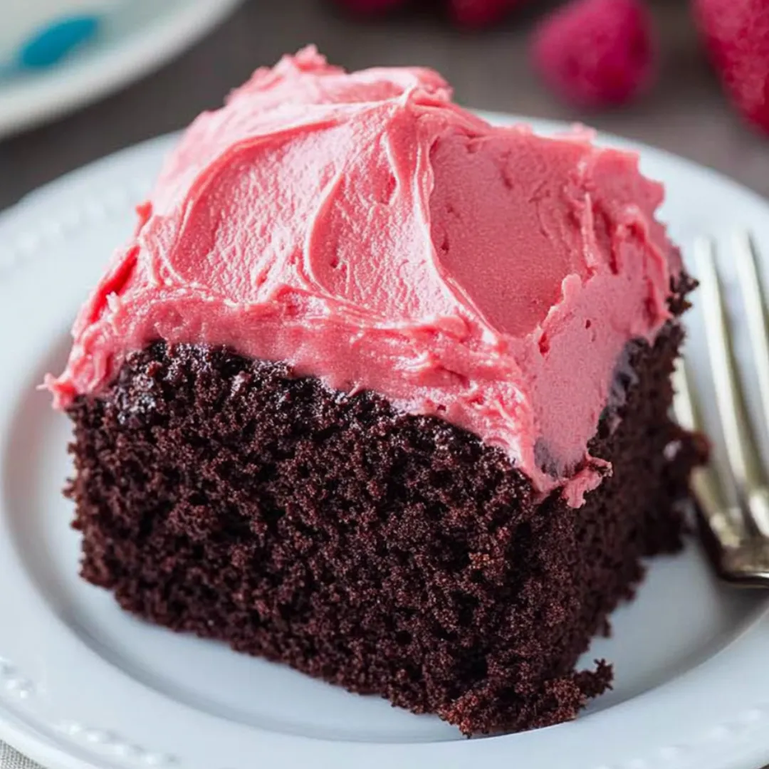 A piece of chocolate cake with pink frosting on a white plate.