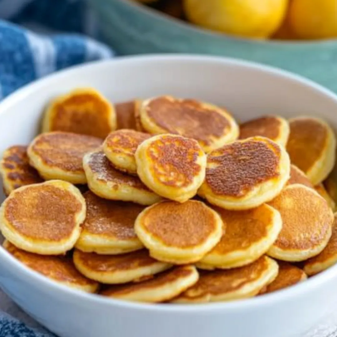 A bowl of pancakes with a lemon wedge on top.