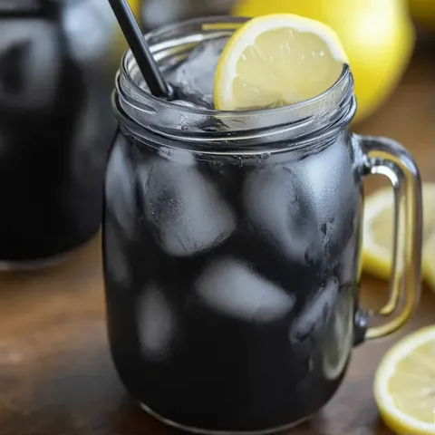 A glass of lemonade with a lemon wedge in it.