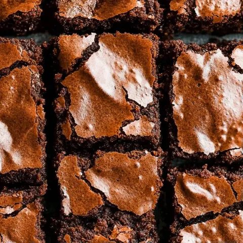 A square of chocolate brownie with white frosting.
