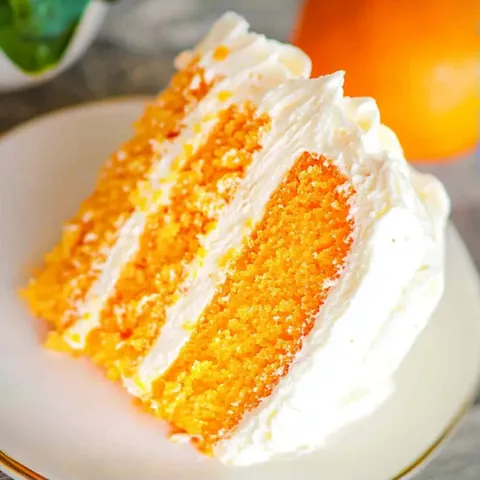 A slice of orange cake on a white plate.