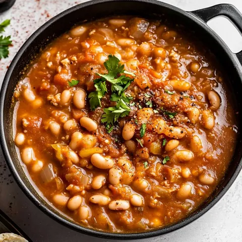 A bowl of beans with a green herb on top.