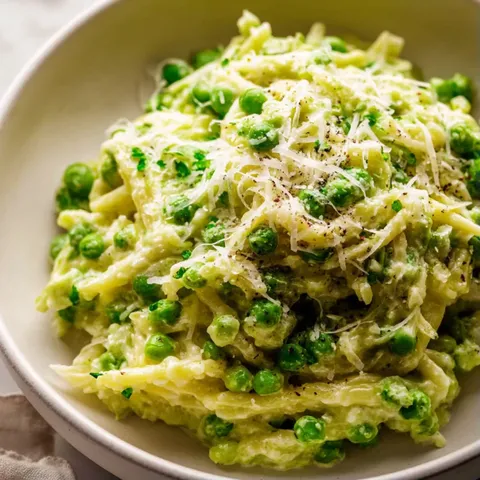 A bowl of pasta with peas and cheese.