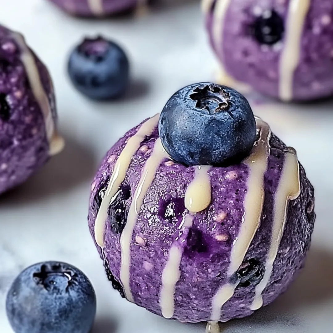 A purple dessert with blueberries and a drizzle of caramel.