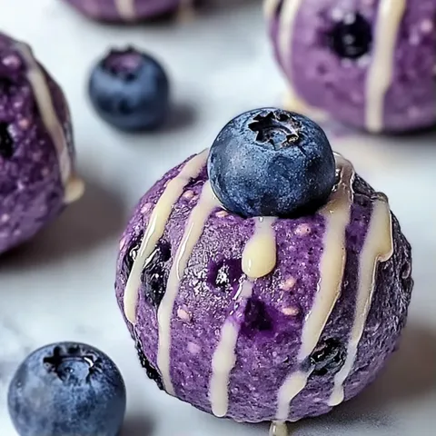 A purple dessert with blueberries and a drizzle of caramel.