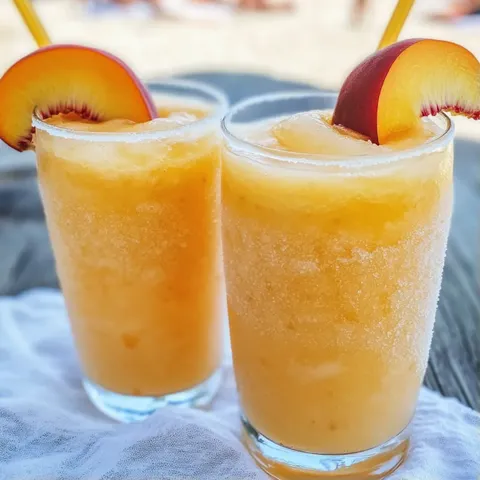 Two glasses of orange juice with sliced apples on top.