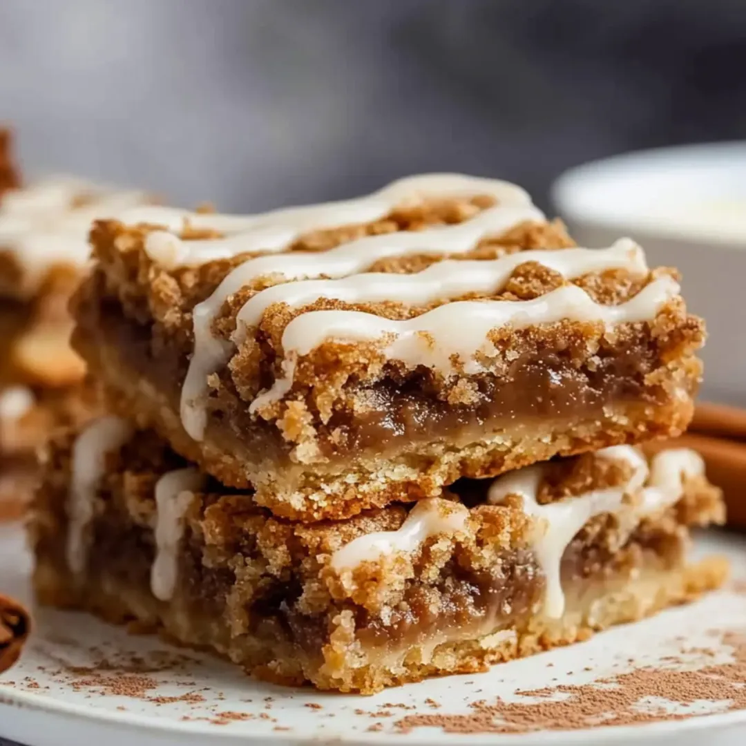 A stack of brownies with white icing.