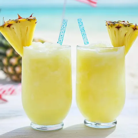 Two glasses of pineapple juice on a table.