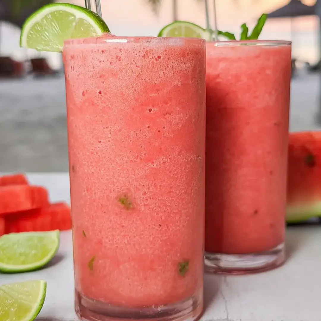 Two glasses filled with bright pink fruity smoothie.