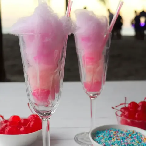 Two glasses with fluffy pink cotton candy inside.