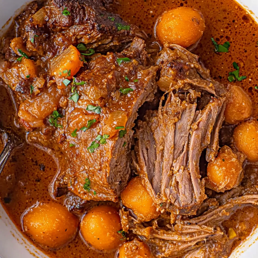 A bowl of beef stew with carrots and potatoes.