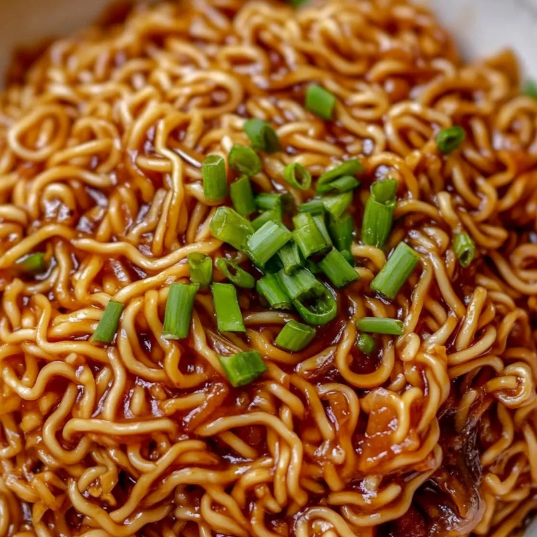 A bowl of noodles with green onions on top.