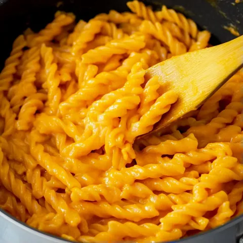 A spoon is in a pot of macaroni and cheese.