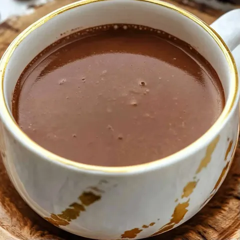 A cup of coffee with a gold rim.