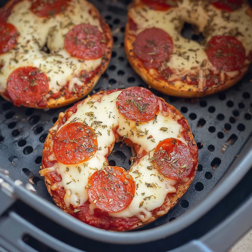 Two pepperoni bagels on a grill.
