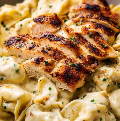 A plate of pasta with chicken on top.