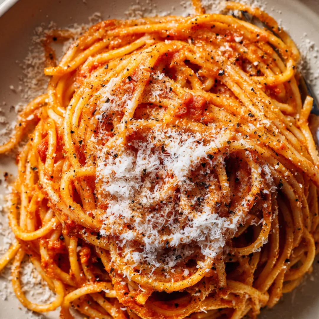 A plate of spaghetti with white cheese on top.