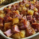 A white bowl filled with ham and potatoes.