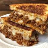 A sandwich with meat and cheese on a white plate.