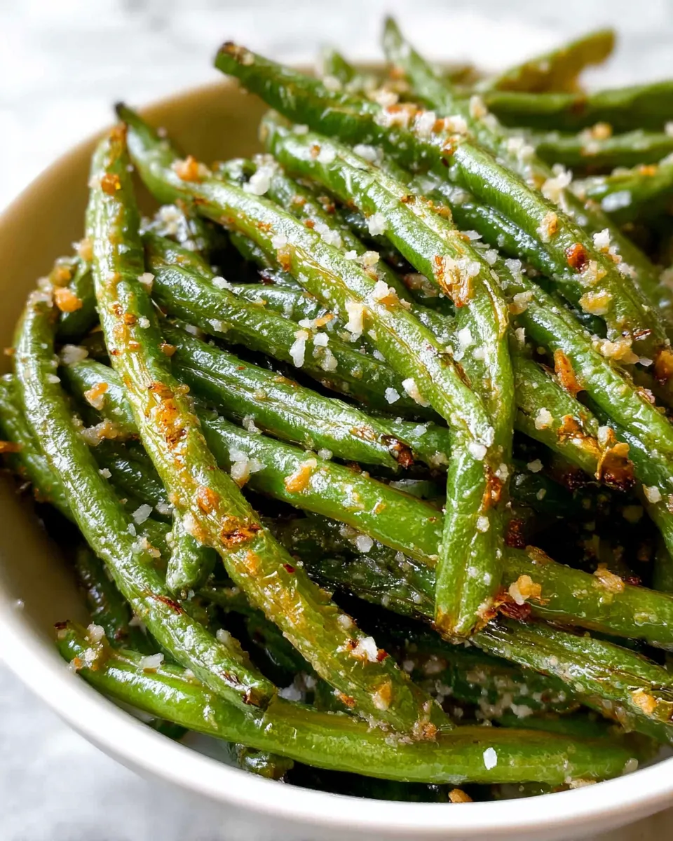 A bowl of green beans with seasoning.