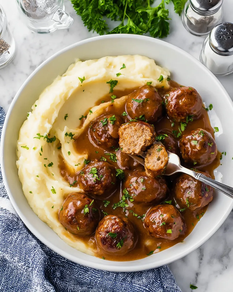 A bowl of food with meatballs and potatoes.