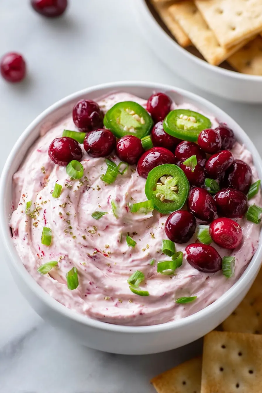 A bowl of food with green and Cranberry toppings.