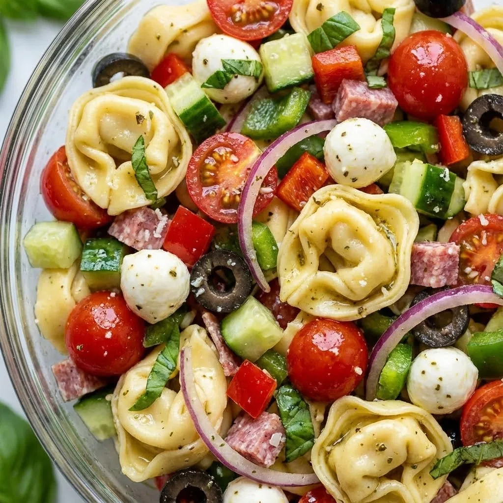A bowl of pasta salad with tomatoes, olives, and cheese.