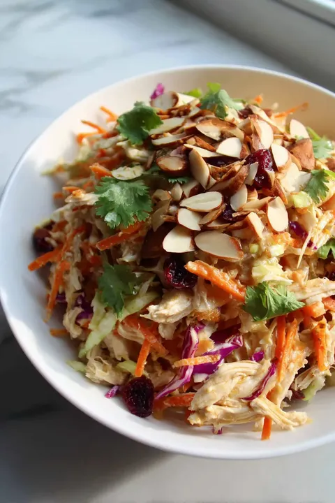 A bowl of food with carrots and almonds.