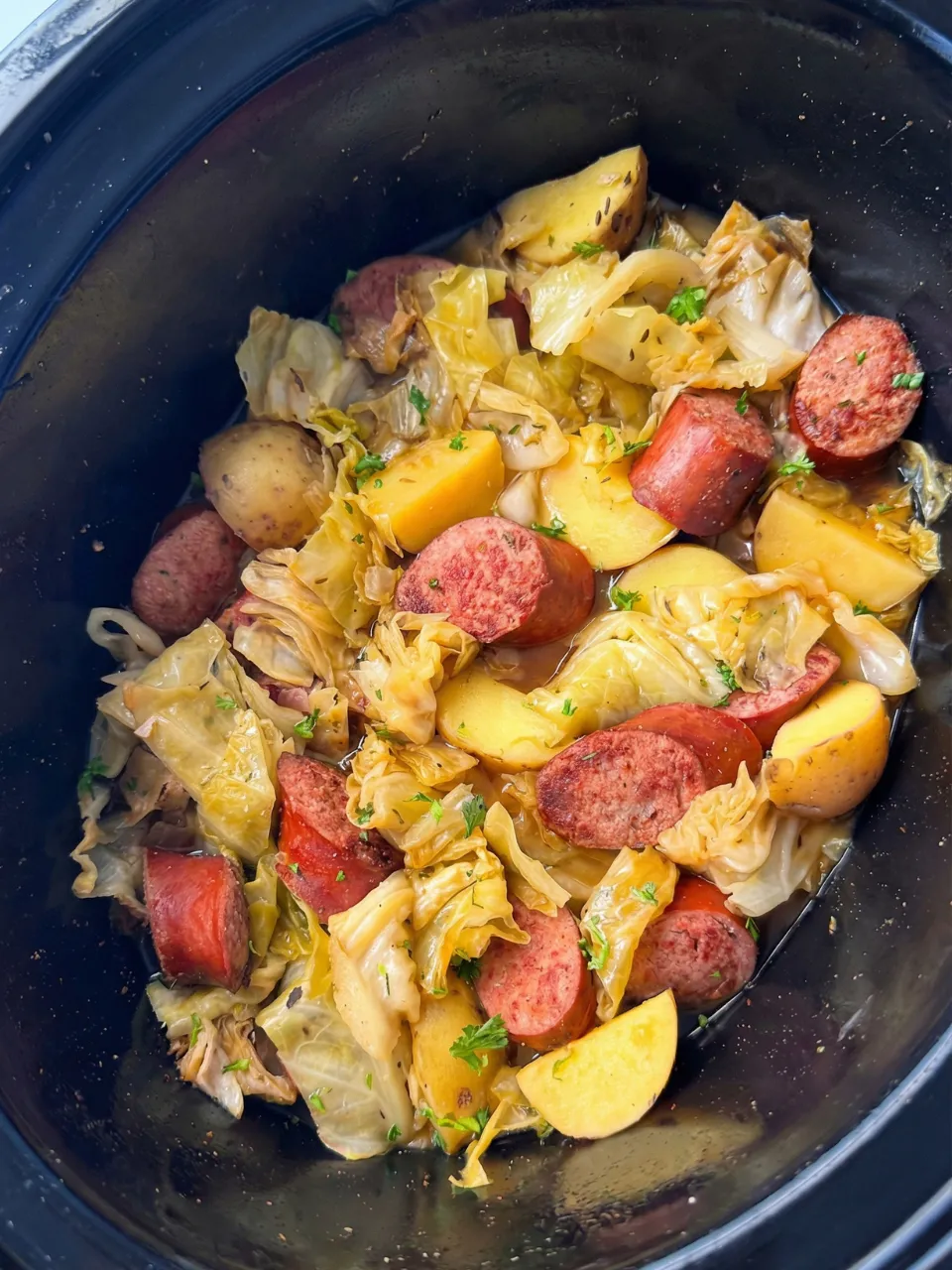 A bowl of food with sausage, potatoes, and cabbage.