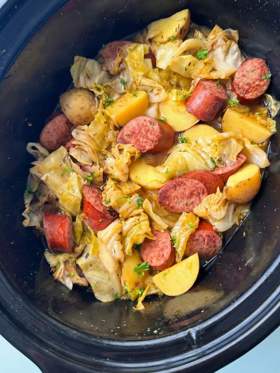 A pot of food with sausage and cabbage.