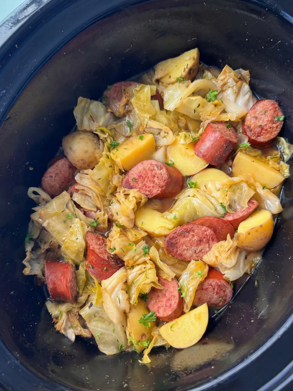 A bowl of food with sausage, potatoes, and cabbage.