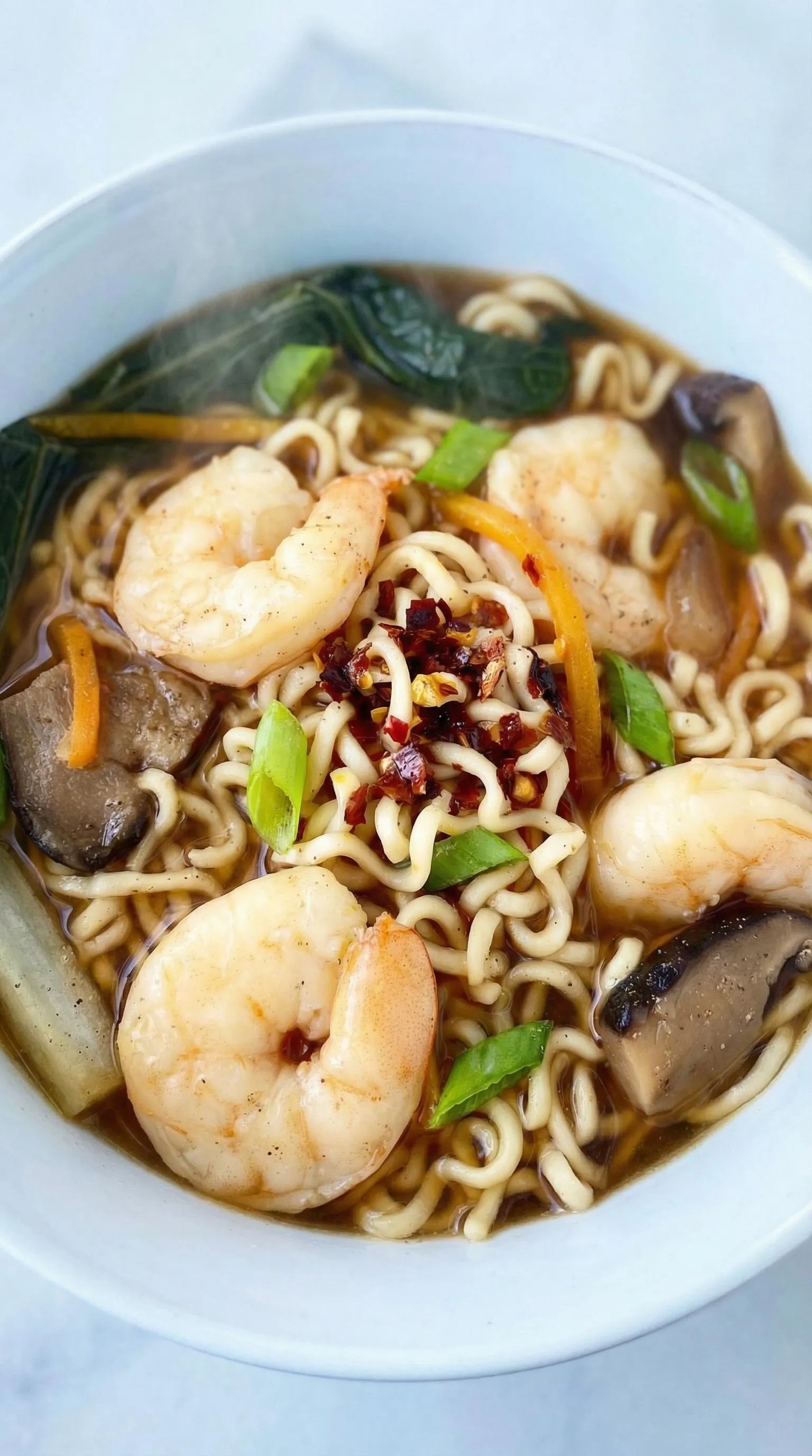 A bowl of soup with shrimp and noodles.