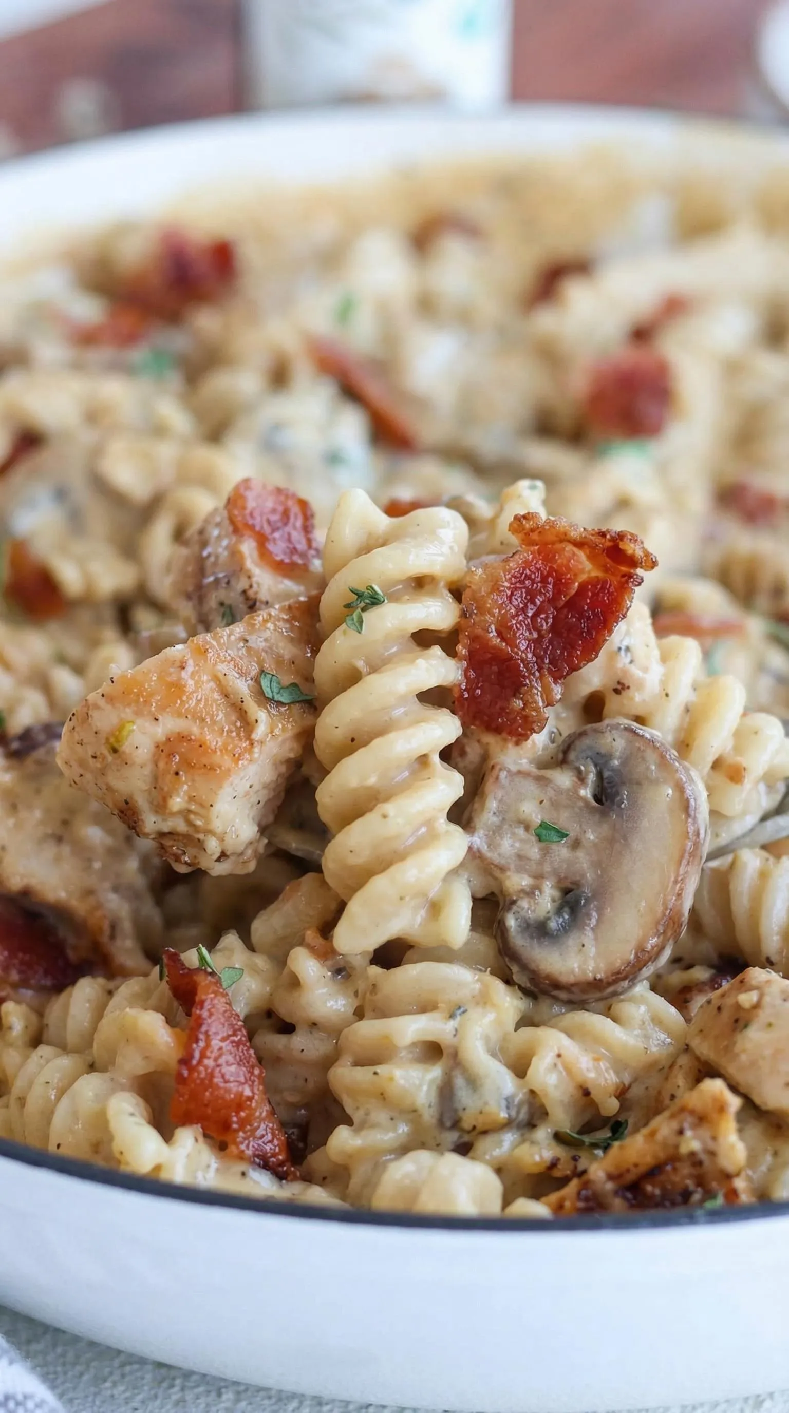 A plate of pasta with bacon and mushrooms.