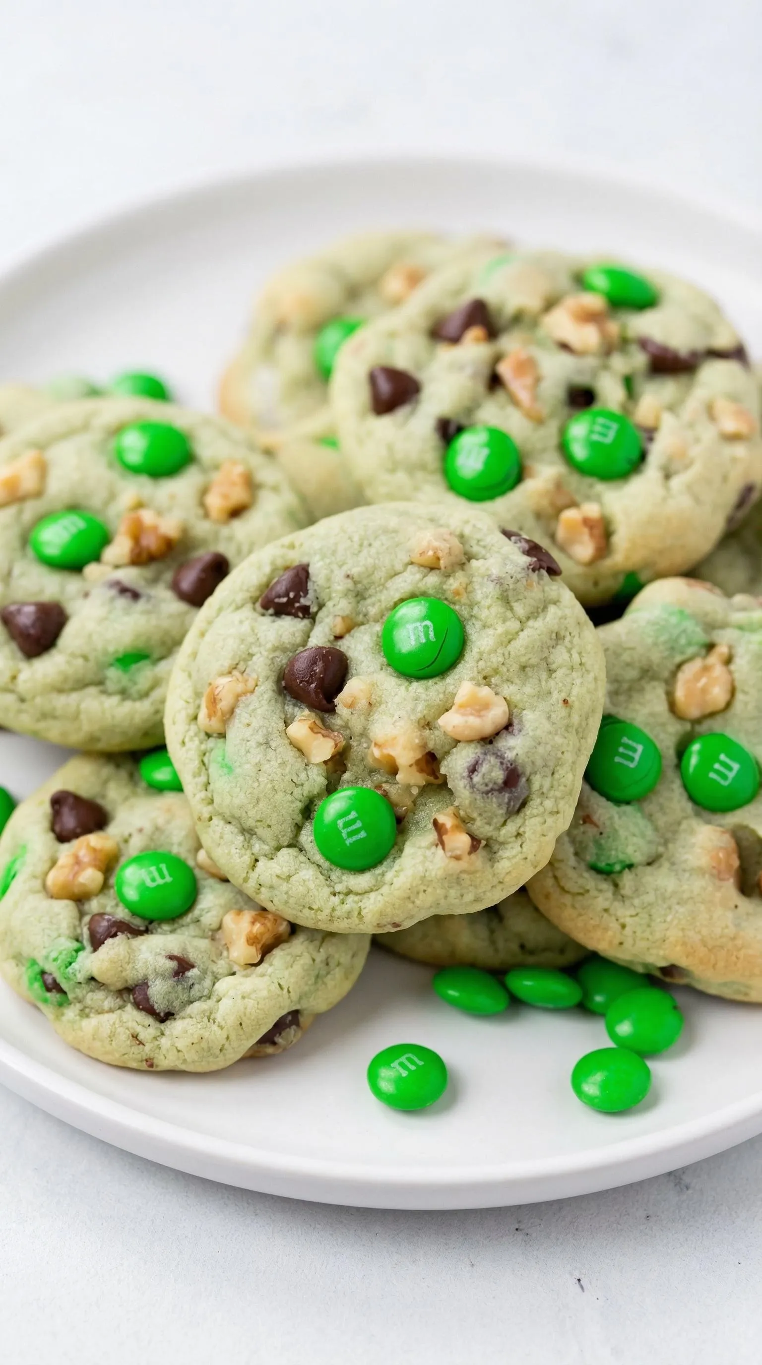 A plate of cookies with green M&M's on top.