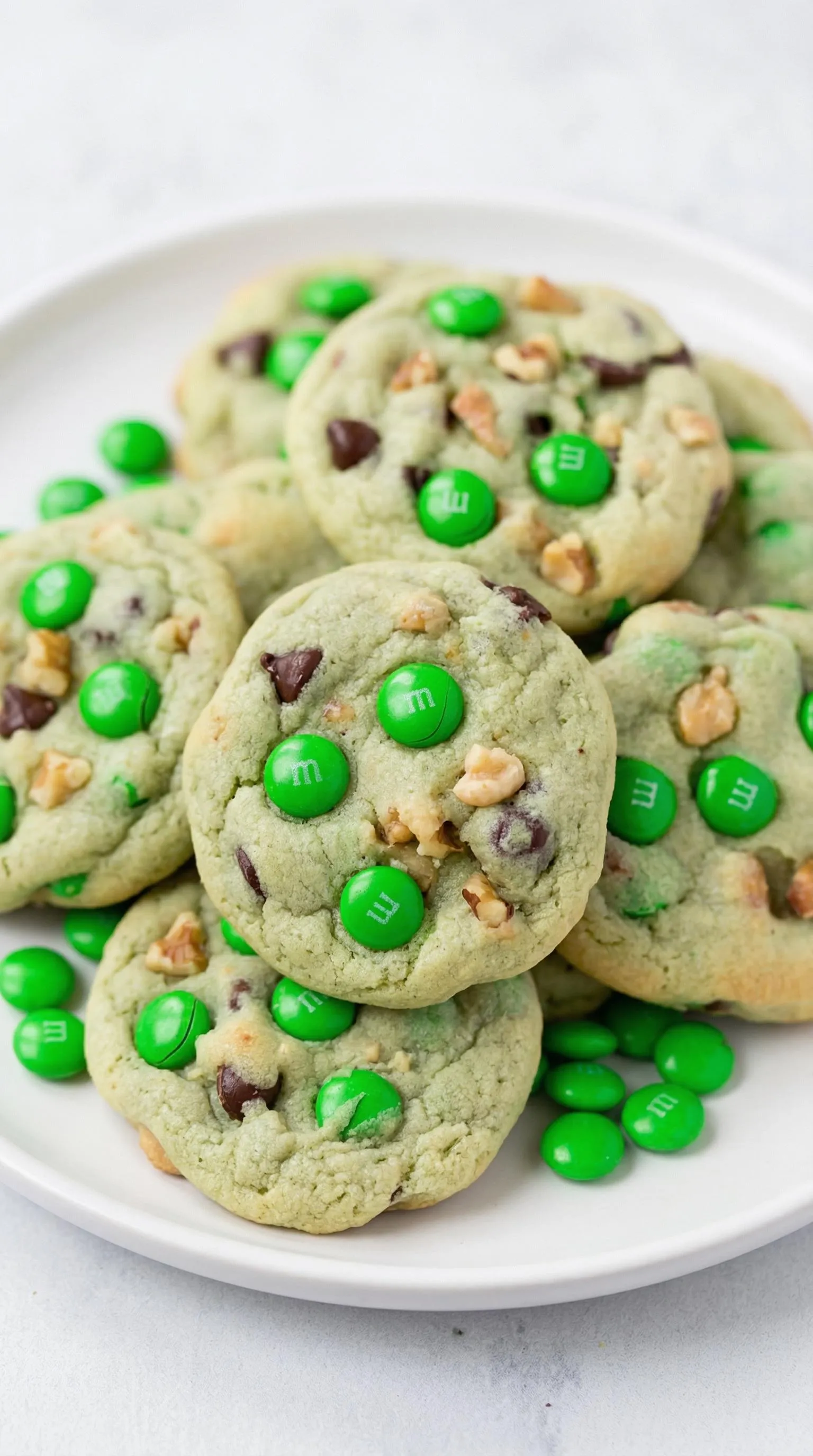 A plate of cookies with green M&Ms on top.