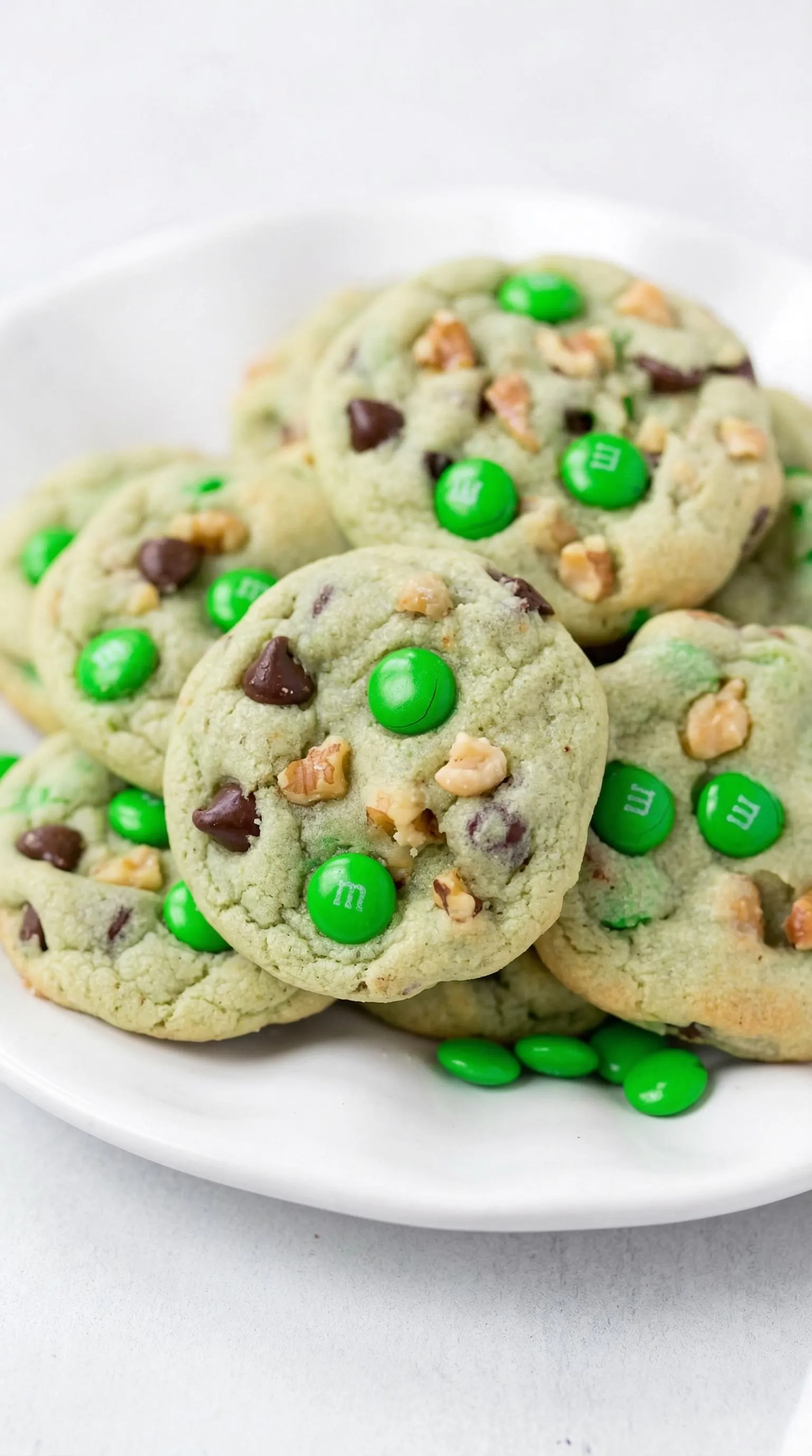 A plate of chocolate chip cookies with green M&Ms.